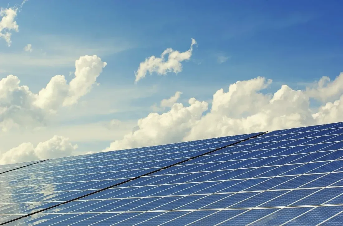 Painéis solares sob um céu azul com nuvens