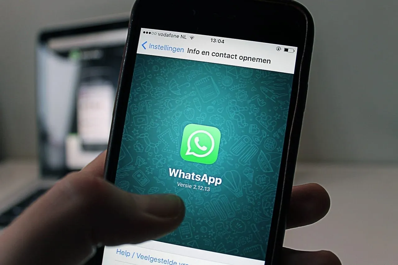 Mão segurando um celular com a tela de abertura do WhatsApp