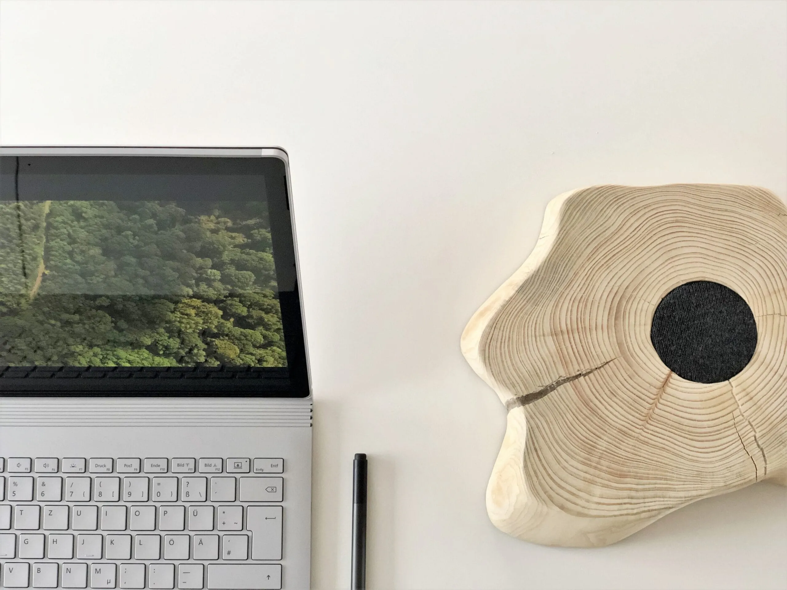 Notebook aberto sobre uma mesa branca ao lado de uma peça decorativa de madeira
