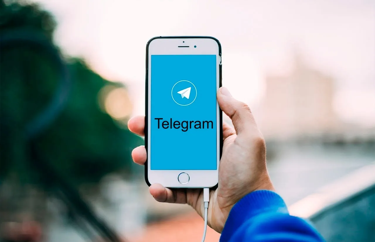 Mão segurando um celular com o aplicativo Telegram aberto