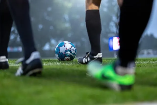 Pés de jogadores e uma bola de futebol em um gramado