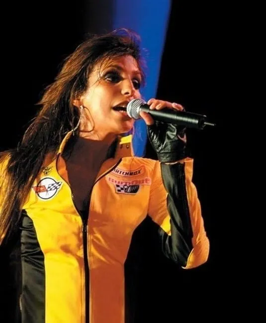 Cantora de jaqueta amarela cantando ao microfone em um palco