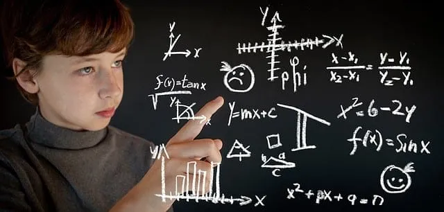 Menino apontando para fórmulas matemáticas escritas em um quadro-negro