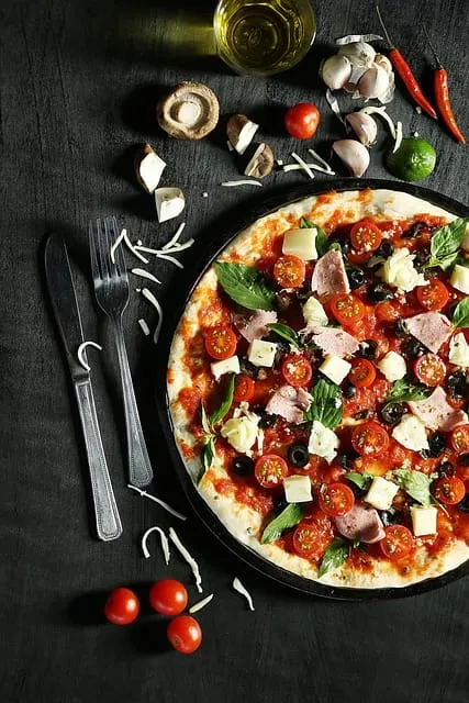 Pizza com tomates, queijo e manjericão vista de cima com talheres e ingredientes