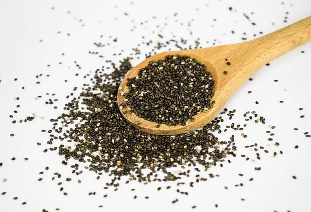 Sementes de chia espalhadas ao redor de uma colher de madeira